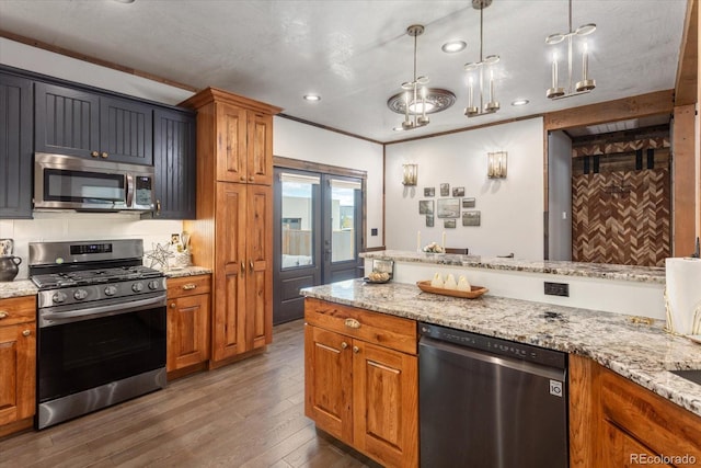 kitchen with appliances with stainless steel finishes, brown cabinetry, and wood finished floors