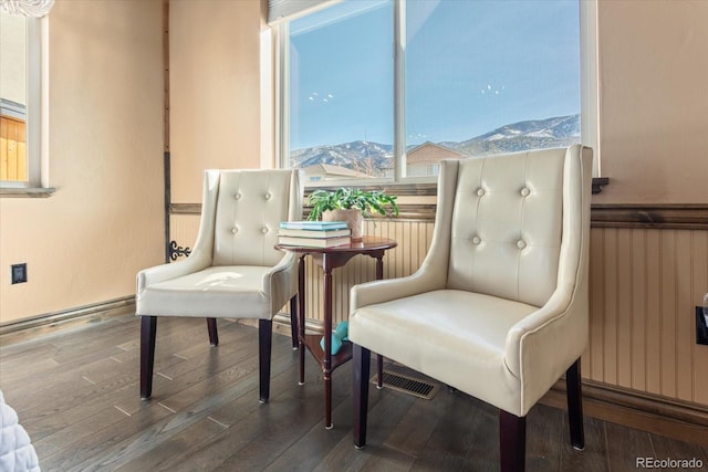 sitting room with a wainscoted wall, a mountain view, a healthy amount of sunlight, and wood finished floors