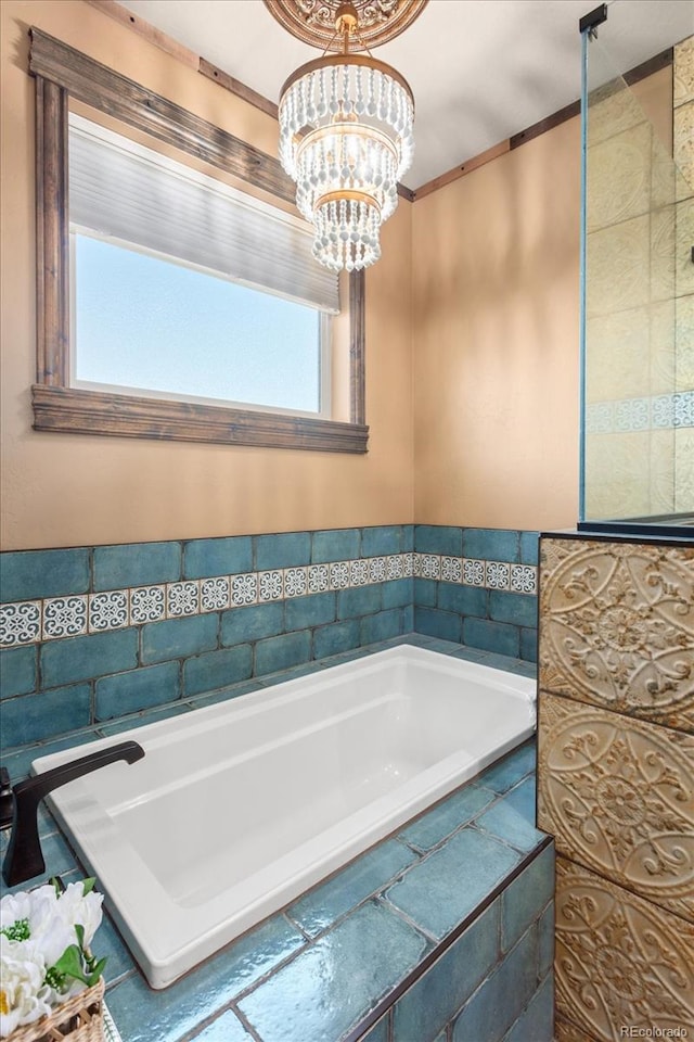 bathroom with plenty of natural light, a garden tub, and a chandelier