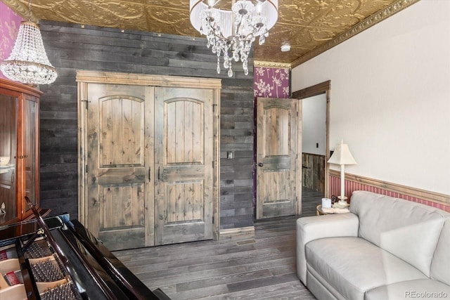living room featuring dark wood-type flooring, wood walls, and a notable chandelier