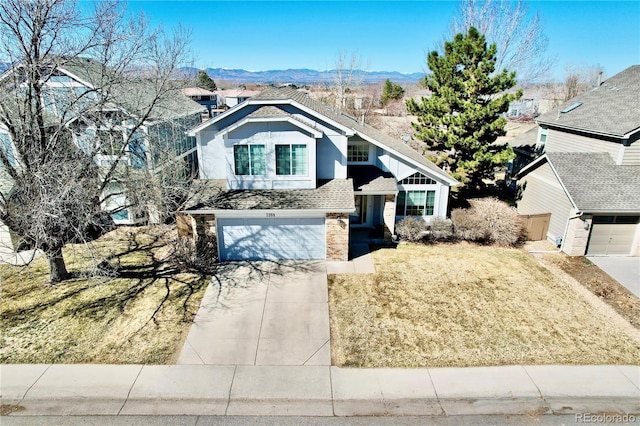 view of front facade with a front yard, driveway, an attached garage, a shingled roof, and a mountain view