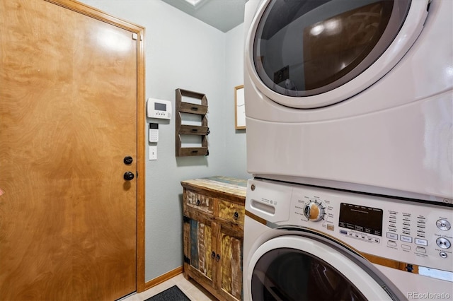 laundry area featuring cabinet space, stacked washer and clothes dryer, and baseboards