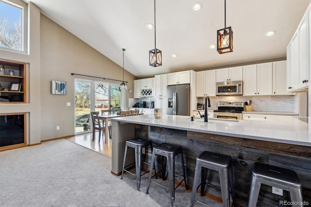 kitchen featuring light countertops, light carpet, appliances with stainless steel finishes, white cabinets, and high vaulted ceiling