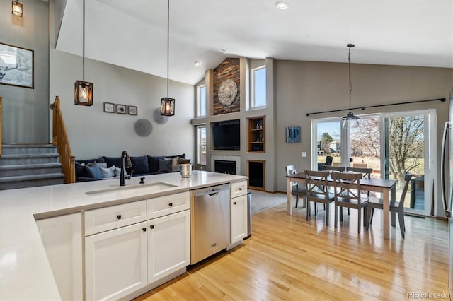 kitchen featuring a sink, stainless steel dishwasher, open floor plan, and white cabinets