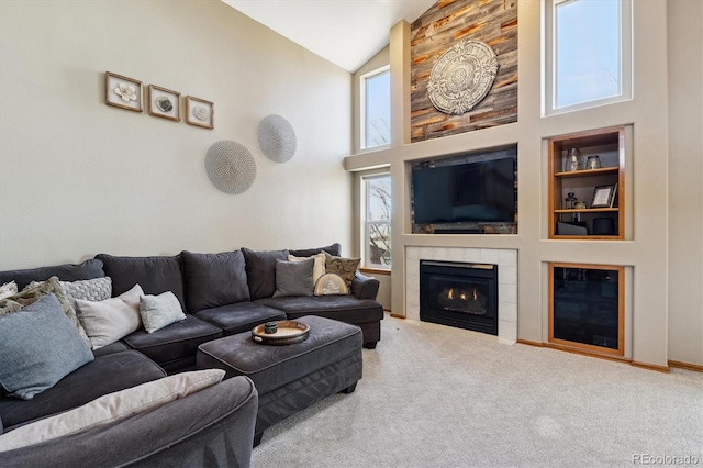 living area featuring baseboards, carpet, built in features, a tile fireplace, and high vaulted ceiling