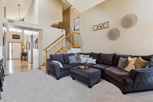 carpeted living room featuring stairway, visible vents, a towering ceiling, and wood finished floors