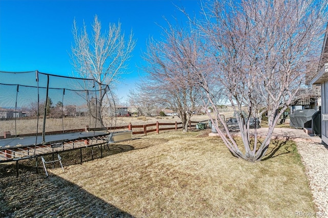 view of yard with a trampoline and fence