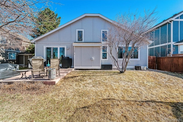 back of property featuring a patio, fence, board and batten siding, and a lawn