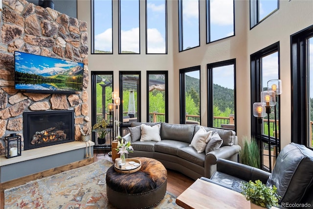 1194 Snyder Mountain Rd, Evergreen, CO 80439 - living area with wood finished floors, a high ceiling, and a stone fireplace