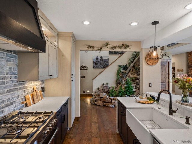1194 Snyder Mountain Rd, Evergreen, CO 80439 - kitchen with wall chimney range hood, light countertops, gas stove, dark wood-type flooring, and decorative light fixtures