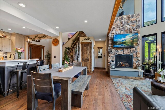 1194 Snyder Mountain Rd, Evergreen, CO 80439 - dining area featuring light wood-style flooring, a stone fireplace, and recessed lighting