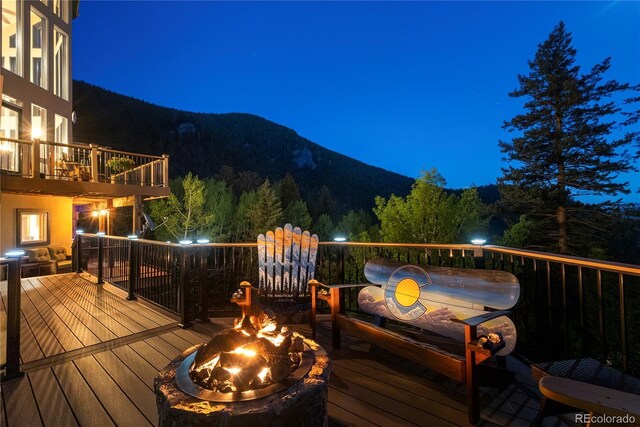 1194 Snyder Mountain Rd, Evergreen, CO 80439 - deck at twilight featuring an outdoor fire pit, a mountain view, and a forest view