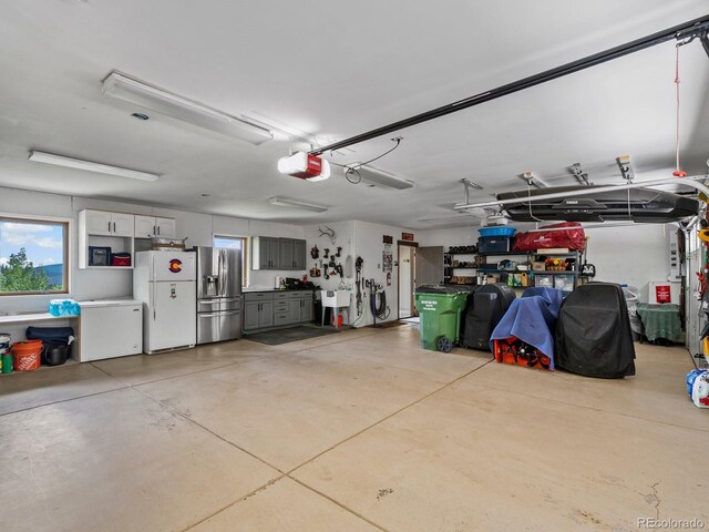 1194 Snyder Mountain Rd, Evergreen, CO 80439 - garage with freestanding refrigerator, a garage door opener, and stainless steel refrigerator with ice dispenser