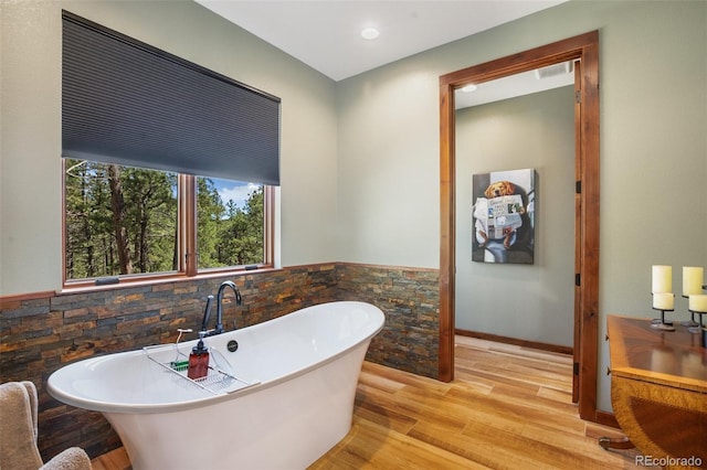 2754 County Rd 421, Florissant, CO 80816 - bathroom with a freestanding bath, wood finished floors, a wainscoted wall, tile walls, and recessed lighting