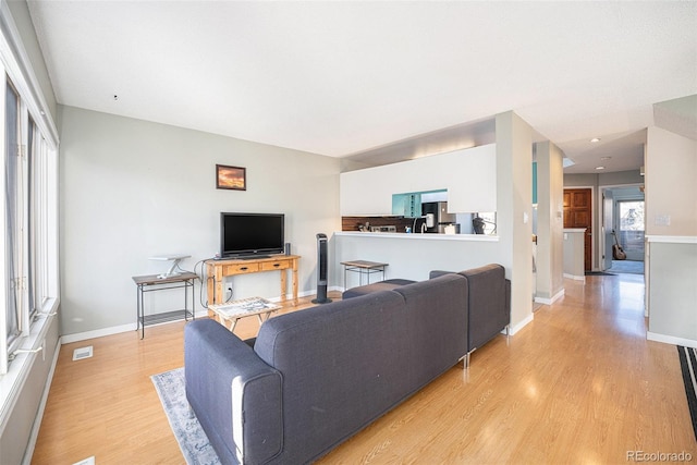 living room featuring light wood finished floors, baseboards, and visible vents