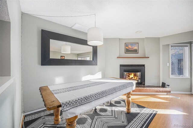 dining area with a glass covered fireplace, visible vents, baseboards, and wood finished floors