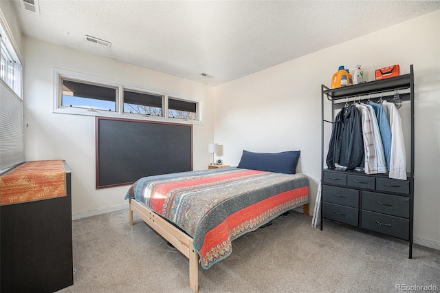 carpeted bedroom featuring a textured ceiling, visible vents, and baseboards