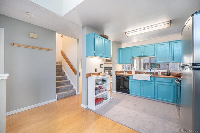 kitchen with stainless steel appliances, light countertops, a sink, and blue cabinetry