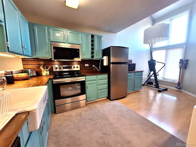 kitchen with stainless steel appliances, butcher block countertops, open shelves, and light wood-style floors