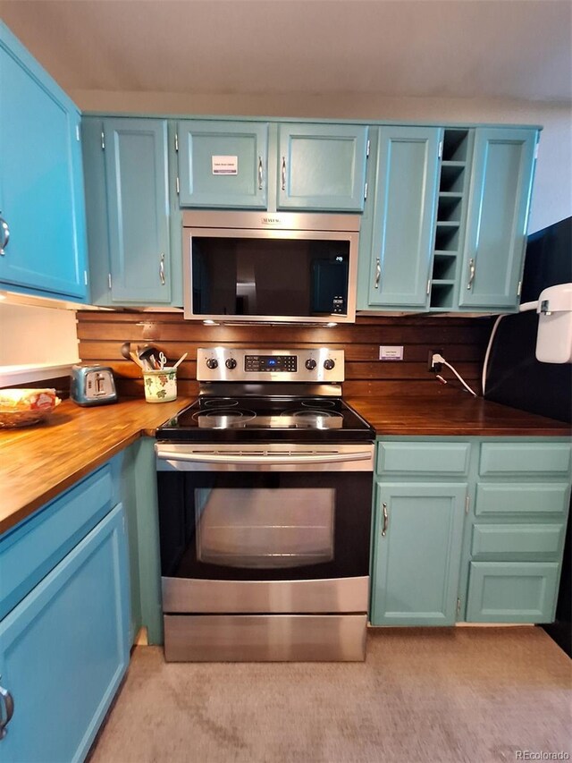 kitchen with blue cabinets, open shelves, appliances with stainless steel finishes, and wooden counters