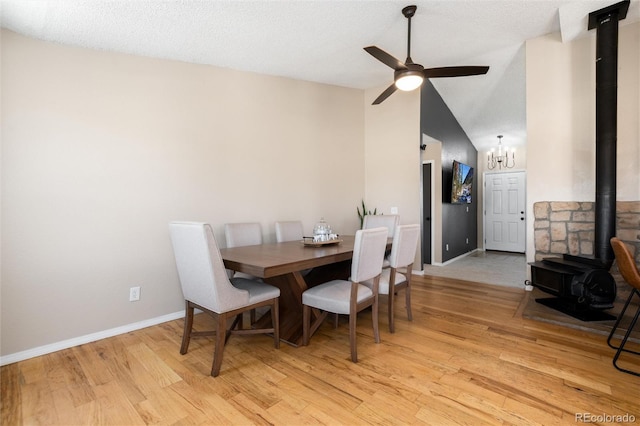 8804 Lariat Loop, Elizabeth, CO 80107 - dining area featuring a wood stove, light wood-type flooring, ceiling fan, a chandelier, and lofted ceiling