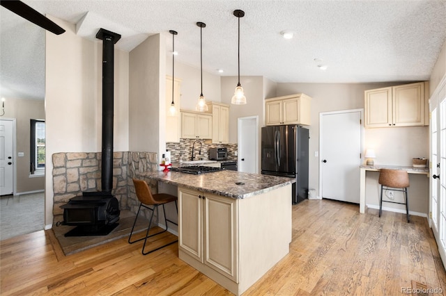 8804 Lariat Loop, Elizabeth, CO 80107 - kitchen with cream cabinetry, refrigerator with ice dispenser, a textured ceiling, a wood stove, and a peninsula