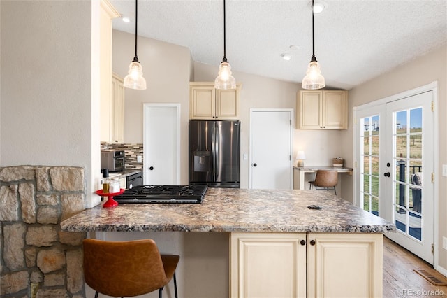 8804 Lariat Loop, Elizabeth, CO 80107 - kitchen with stainless steel fridge, cream cabinets, backsplash, a peninsula, and a textured ceiling
