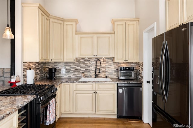 8804 Lariat Loop, Elizabeth, CO 80107 - kitchen featuring cream cabinets, black fridge, dishwasher, range with gas cooktop, and light stone counters
