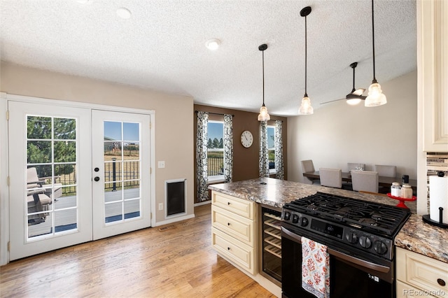8804 Lariat Loop, Elizabeth, CO 80107 - kitchen featuring gas range oven, cream cabinetry, a textured ceiling, a peninsula, and light wood-style floors