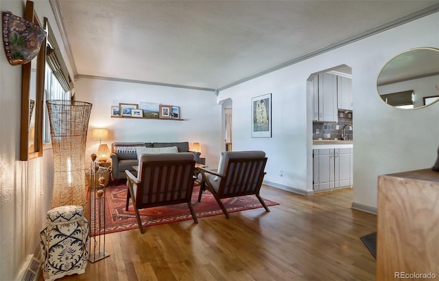 bedroom featuring arched walkways, crown molding, wood finished floors, and baseboards