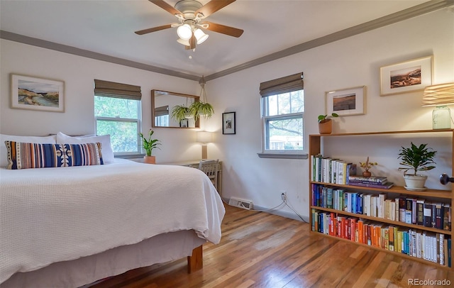 bedroom with multiple windows, wood finished floors, and crown molding