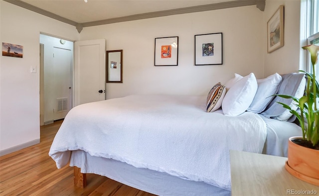 bedroom featuring light wood-style floors, crown molding, and baseboards