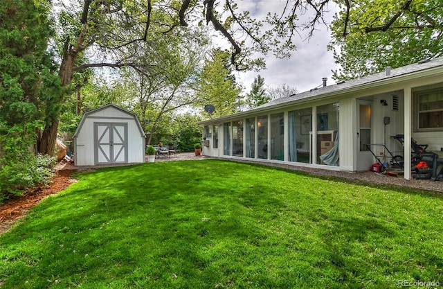 view of green lawn with a shed, an outbuilding, a patio, and a sunroom