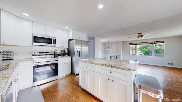 11718 Keough Dr, Northglenn, CO 80233 - kitchen featuring appliances with stainless steel finishes, light wood finished floors, a ceiling fan, white cabinets, and recessed lighting