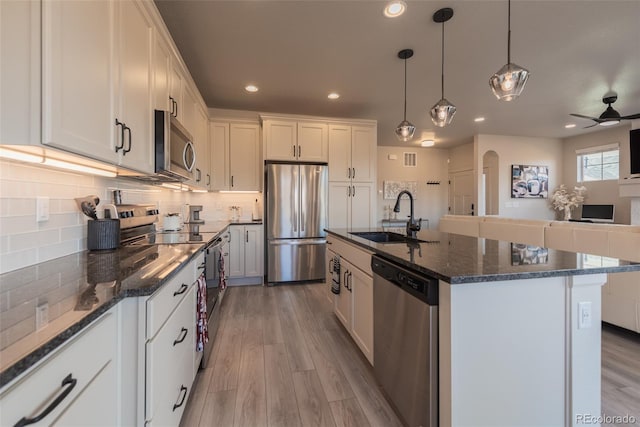 kitchen featuring a sink, light wood-type flooring, backsplash, and appliances with stainless steel finishes