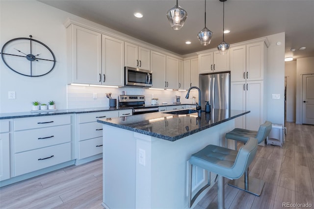 kitchen featuring a breakfast bar area, white cabinets, stainless steel appliances, and a sink