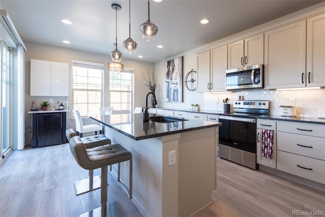 kitchen with a sink, light wood finished floors, backsplash, and stainless steel appliances