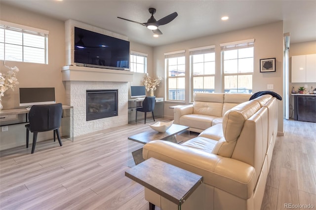 living room with light wood-type flooring, recessed lighting, a fireplace, baseboards, and ceiling fan