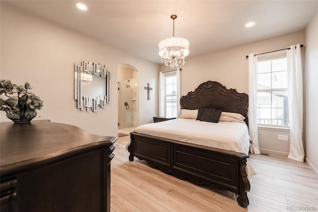 bedroom featuring arched walkways, a notable chandelier, multiple windows, and light wood-style floors