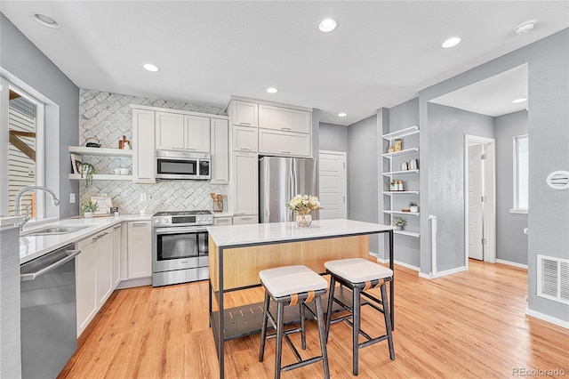 1903 W 66th Ave, Denver, CO 80221 - kitchen featuring appliances with stainless steel finishes, open shelves, light wood-type flooring, light countertops, and tasteful backsplash