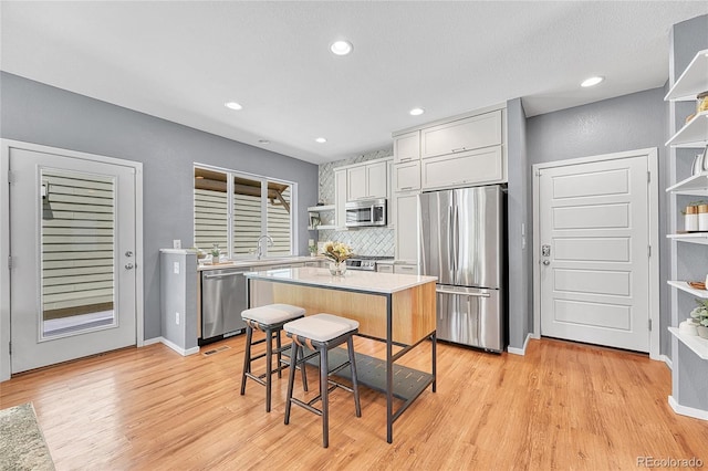 1903 W 66th Ave, Denver, CO 80221 - kitchen with appliances with stainless steel finishes, open shelves, light wood-style floors, light countertops, and decorative backsplash