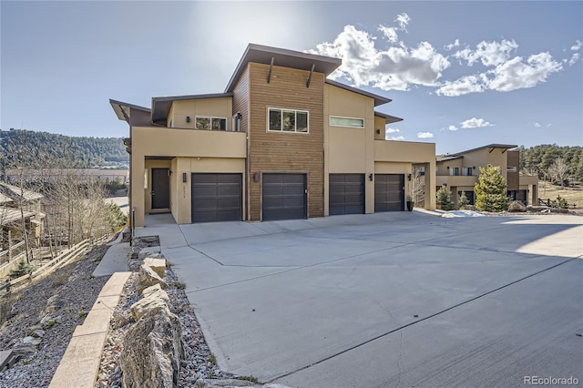 28424 Tepees Way, Evergreen, CO 80439 - contemporary house featuring driveway, an attached garage, and stucco siding