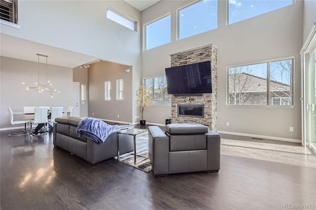 28424 Tepees Way, Evergreen, CO 80439 - living room featuring a high ceiling, dark wood-style floors, a chandelier, and a stone fireplace