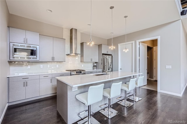 28424 Tepees Way, Evergreen, CO 80439 - kitchen featuring wall chimney exhaust hood, appliances with stainless steel finishes, dark wood-style flooring, tasteful backsplash, and a kitchen island with sink