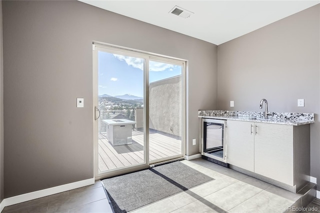 28424 Tepees Way, Evergreen, CO 80439 - kitchen with wine cooler, light tile patterned floors, white cabinets, light stone counters, and a mountain view
