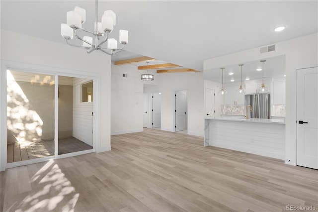 unfurnished living room with light wood finished floors, visible vents, a notable chandelier, beam ceiling, and recessed lighting