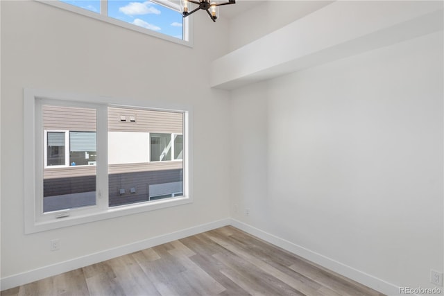 spare room with a chandelier, wood finished floors, and baseboards