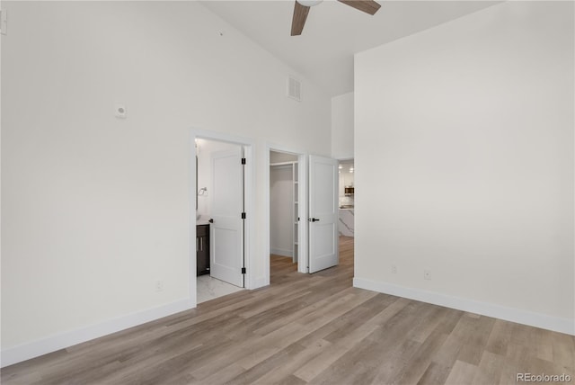 unfurnished bedroom with high vaulted ceiling, wood finished floors, visible vents, and baseboards