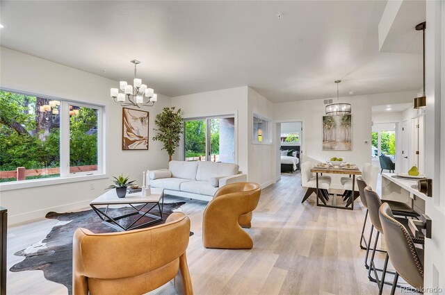 living room with baseboards, an inviting chandelier, and light wood-style floors