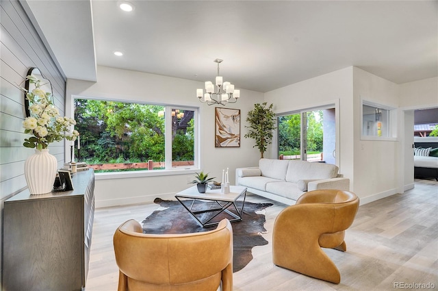 living room with baseboards, recessed lighting, light wood-type flooring, and a notable chandelier